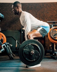 a man doing squats with a barbell in a gym