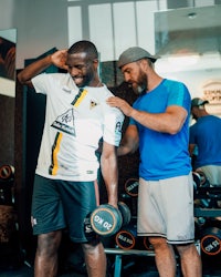 two men standing next to each other in a gym