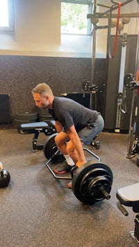 a man squatting with a barbell in a gym