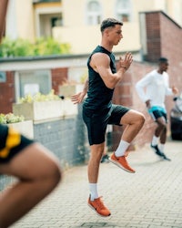 a group of men doing a squat exercise on a street