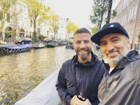 two men taking a selfie in front of a canal