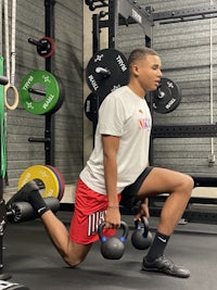 a young man in a gym doing a kettlebell squat